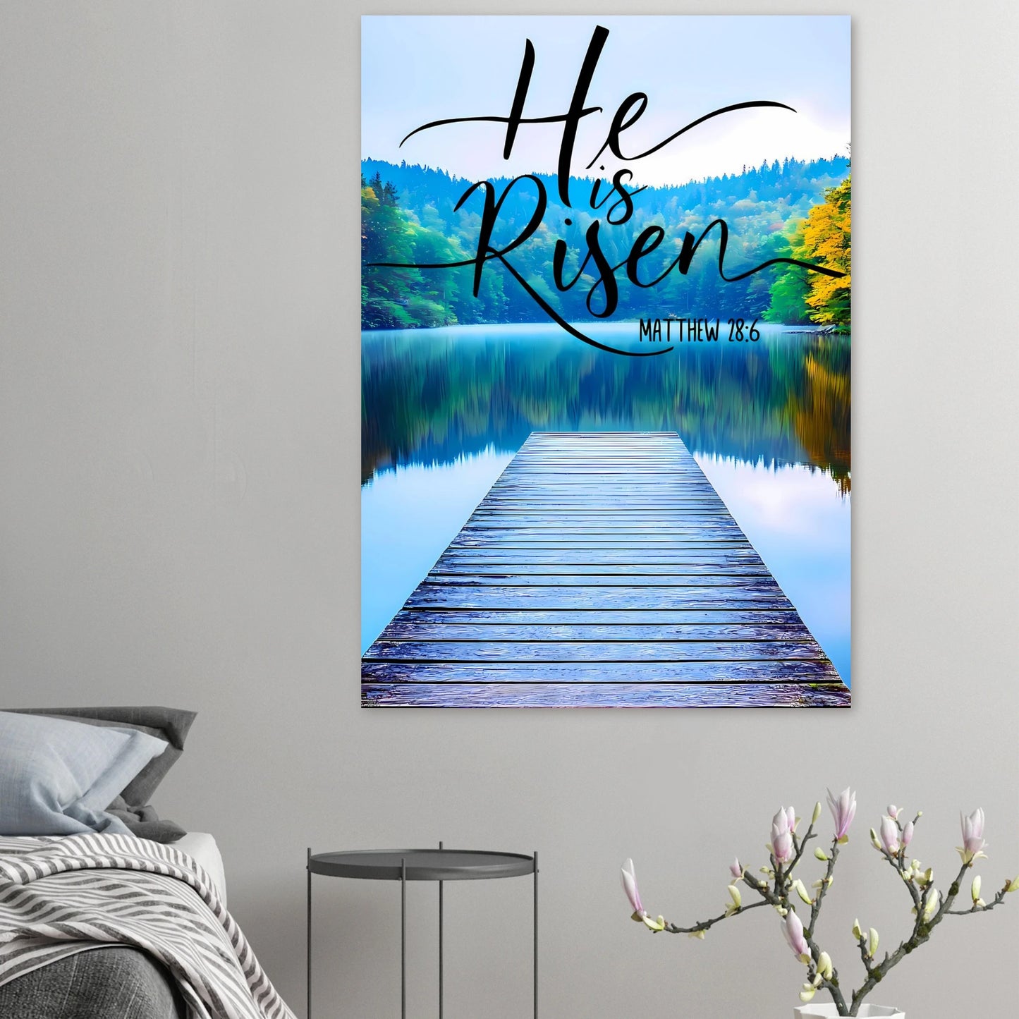 Canvas print with 'He is Risen' text over a lake and dock scene, displayed on a wall.