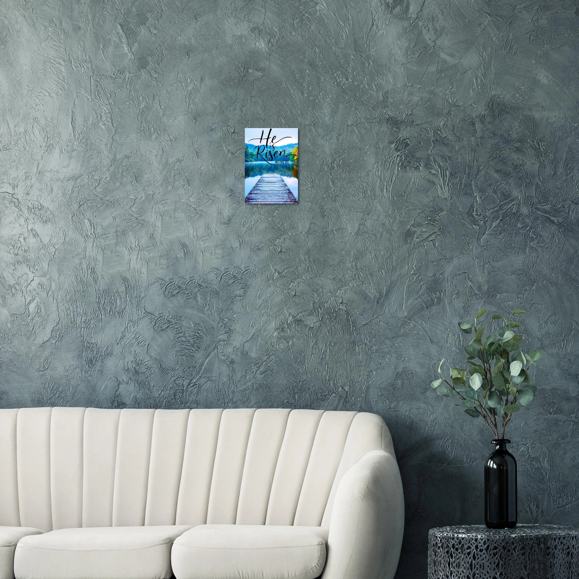 Wall art on a textured gray wall above a beige sofa with a plant on a side table.