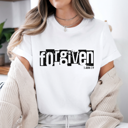 Person wearing a white t-shirt with 'Forgiven' text, standing indoors.