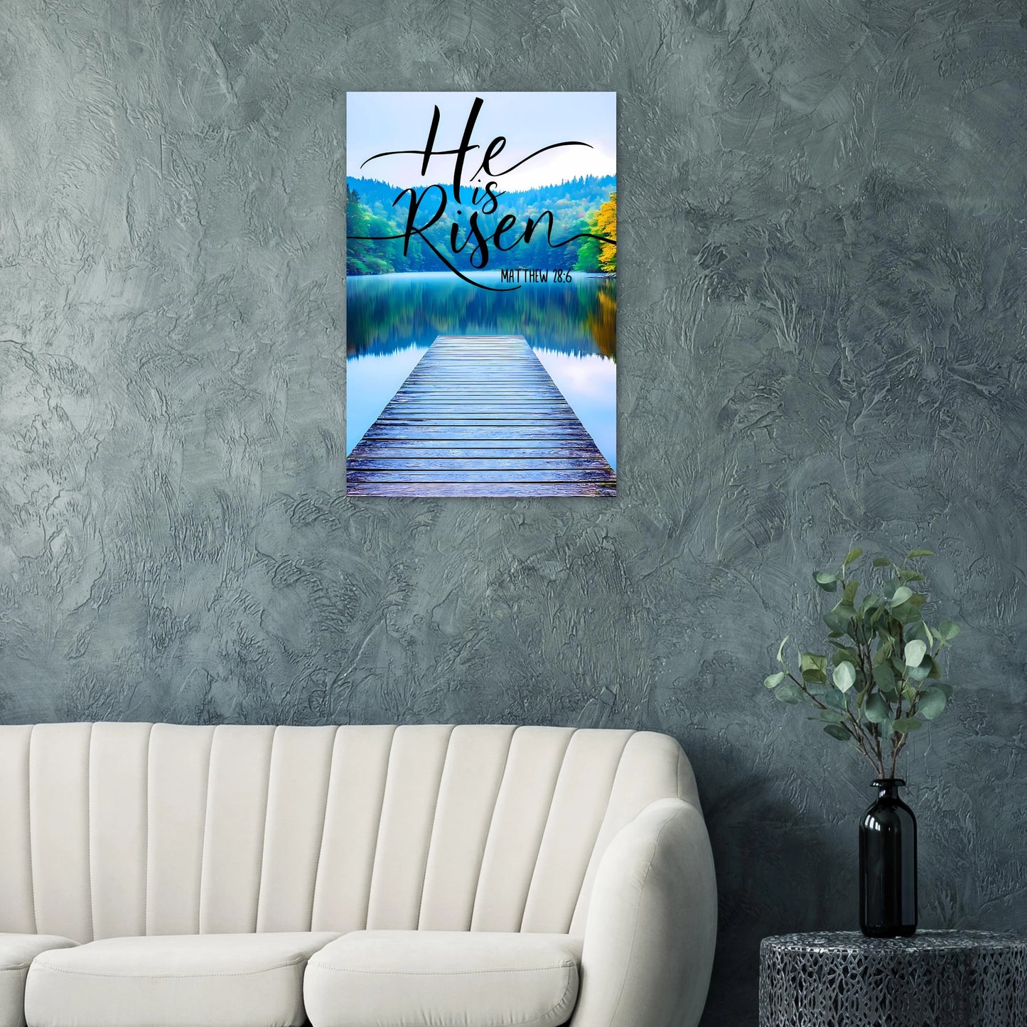 Wall art with 'He is Risen' text over a lake scene in a living room.