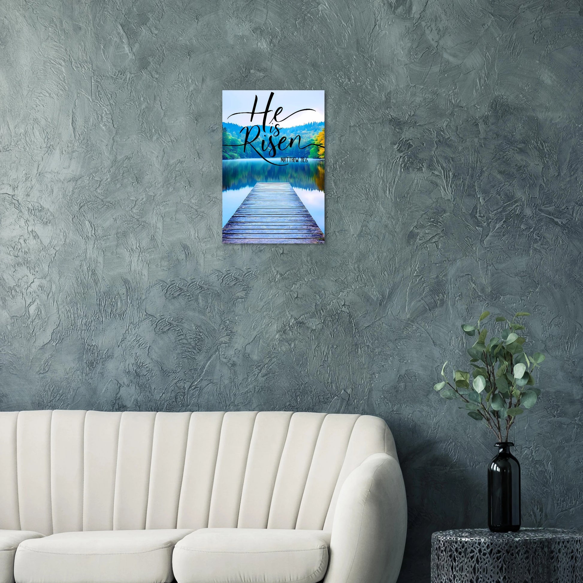 Wall art with 'He is Risen' text over a lake scene in a living room.