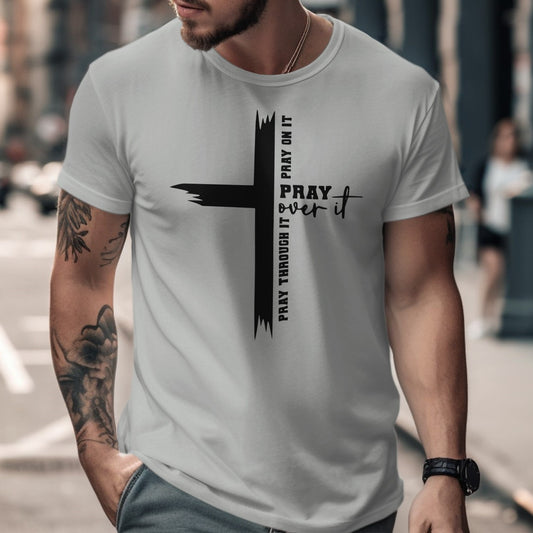 Man wearing a white t-shirt with a black cross design and text on a city street.